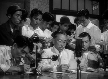Movie still from “Godzilla” (1954), directed by Ishirô Honda – A group of people sitting around a table; Medium shot, High angle