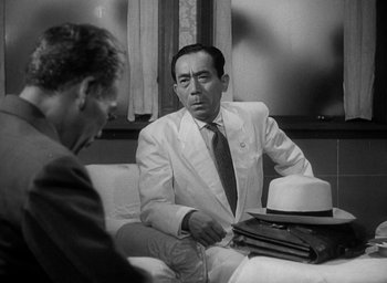 Movie still from “Godzilla” (1954), directed by Ishirô Honda – A man wearing a white suit and a white hat; Medium shot, Over the shoulder angle