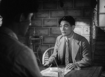 Movie still from “Godzilla” (1954), directed by Ishirô Honda – A man sitting at a table in front of another man; Medium shot, Over the shoulder angle