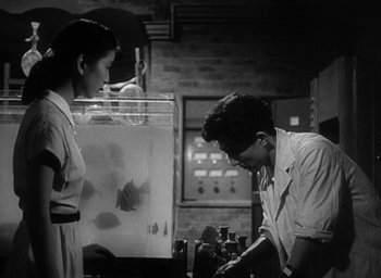 Movie still from “Godzilla” (1954), directed by Ishirô Honda – A man and a woman looking at a fish tank in a room; Medium shot, Low angle