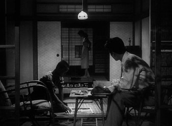 Movie still from “Godzilla” (1954), directed by Ishirô Honda – A man and a woman playing a game of chess; Wide shot, Low angle