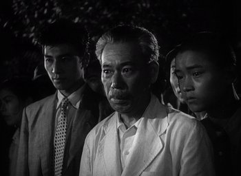 Movie still from “Godzilla” (1954), directed by Ishirô Honda – A group of men standing next to each other; Close Up shot, Low angle
