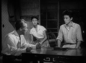 Movie still from “Godzilla” (1954), directed by Ishirô Honda – A group of people sitting around a table; Medium shot, High angle