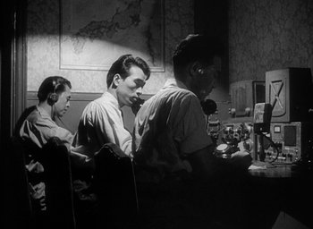Movie still from “Godzilla” (1954), directed by Ishirô Honda – A group of people sitting around a table; Medium shot, Low angle