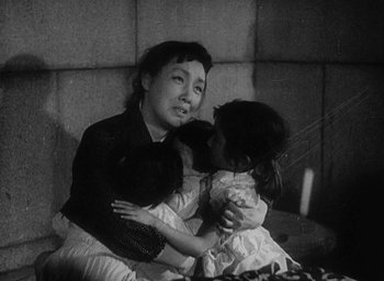 Movie still from “Godzilla” (1954), directed by Ishirô Honda – An old photo of a woman holding a child; Medium shot, High angle