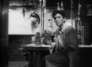 Movie still from “Godzilla” (1954), directed by Ishirô Honda – A black and white photo of a man sitting at a table; Medium shot, Low angle