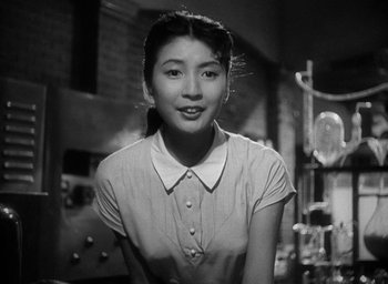 Movie still from “Godzilla” (1954), directed by Ishirô Honda – An asian woman in a white shirt is posing for a picture; Medium shot, Low angle