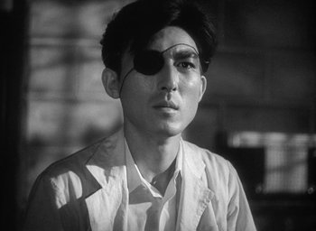Movie still from “Godzilla” (1954), directed by Ishirô Honda – A young man wearing an eyepatch is looking at the camera; Close Up shot, Low angle