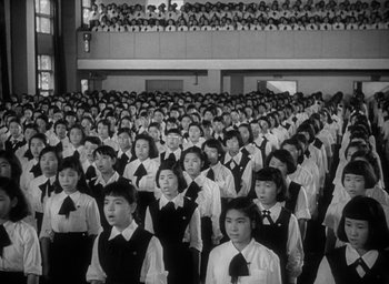 Movie still from “Godzilla” (1954), directed by Ishirô Honda – A large group of people standing in front of a building; Extreme Wide shot, High angle