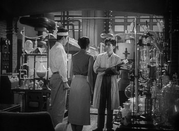 Movie still from “Godzilla” (1954), directed by Ishirô Honda – A group of people standing around in a room; Medium shot, Low angle