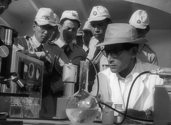 Movie still from “Godzilla” (1954), directed by Ishirô Honda – A group of men in hats and glasses working in a lab; Medium shot, High angle