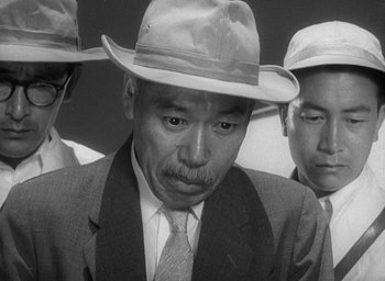 Movie still from “Godzilla” (1954), directed by Ishirô Honda – A group of men in suits and hats; Close Up shot, Low angle