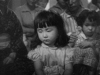 Movie still from “Godzilla: King of the Monsters!” (1956), directed by Ishirô Honda – A little girl sitting in front of a group of people; Close Up shot, High angle