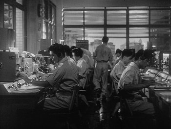 Movie still from “Godzilla: King of the Monsters!” (1956), directed by Ishirô Honda – A black and white photo of people sitting at tables; Wide shot, Low angle