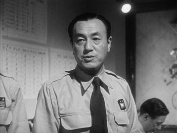 Movie still from “Godzilla: King of the Monsters!” (1956), directed by Ishirô Honda – An old black and white photo of a man in a uniform; Close Up shot, Low angle