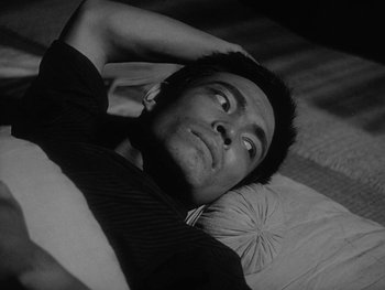 Movie still from “Godzilla: King of the Monsters!” (1956), directed by Ishirô Honda – A black and white photo of a man laying in bed; Close Up shot, High angle