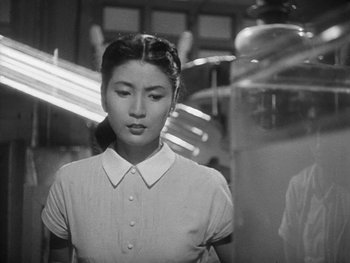 Movie still from “Godzilla: King of the Monsters!” (1956), directed by Ishirô Honda – A woman in a white shirt is standing in front of a mirror; Close Up shot, Low angle