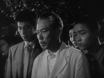 Movie still from “Godzilla: King of the Monsters!” (1956), directed by Ishirô Honda – An old photo of a group of men standing together; Close Up shot, Low angle