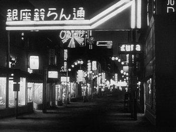 Movie still from “Godzilla: King of the Monsters!” (1956), directed by Ishirô Honda – A black - and - white photo of an asian city street at night; Extreme Wide shot, Low angle
