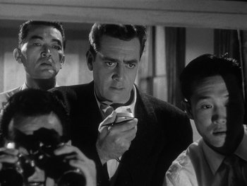 Movie still from “Godzilla: King of the Monsters!” (1956), directed by Ishirô Honda – A group of men standing next to each other in a room; Medium shot, Low angle