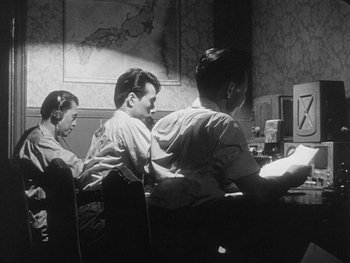Movie still from “Godzilla: King of the Monsters!” (1956), directed by Ishirô Honda – A group of people sitting at a table with computers on it; Medium shot, Low angle