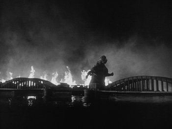 Movie still from “Godzilla: King of the Monsters!” (1956), directed by Ishirô Honda – A man standing on a bridge in the middle of the night; Wide shot, Low angle