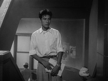 Movie still from “Godzilla: King of the Monsters!” (1956), directed by Ishirô Honda – A black and white photo of a man holding a paper; Medium shot, Low angle