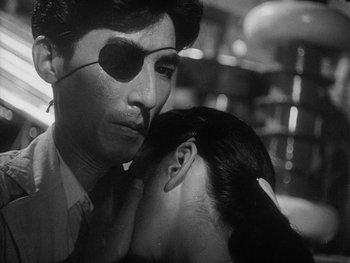 Movie still from “Godzilla: King of the Monsters!” (1956), directed by Ishirô Honda – A black and white photo of a man and a woman kissing; Close Up shot, Over the shoulder angle