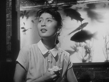 Movie still from “Godzilla: King of the Monsters!” (1956), directed by Ishirô Honda – An asian woman holding a flower in her hand; Medium shot, Low angle