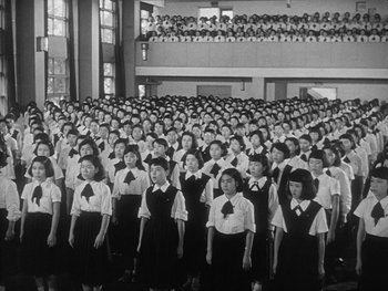 Movie still from “Godzilla: King of the Monsters!” (1956), directed by Ishirô Honda – A group of young women standing in front of an audience; Extreme Wide shot, High angle