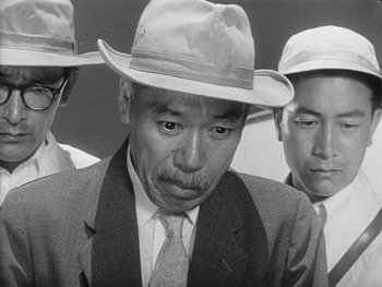 Movie still from “Godzilla: King of the Monsters!” (1956), directed by Ishirô Honda – A group of men wearing hats and suits; Close Up shot, Low angle