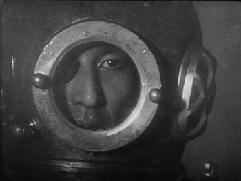 Movie still from “Godzilla: King of the Monsters!” (1956), directed by Ishirô Honda – A black and white photo of a man wearing a diving helmet; Close Up shot, High angle