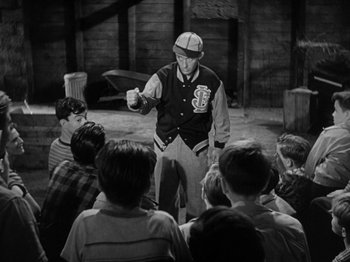 Movie still from “Going My Way” (1944), directed by Leo McCarey – A man holding a baseball bat in front of a group of kids; Medium shot, Over the shoulder angle