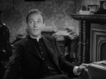 Movie still from “Going My Way” (1944), directed by Leo McCarey – A black and white photo of a man sitting in a chair; Medium shot, High angle