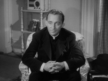 Movie still from “Going My Way” (1944), directed by Leo McCarey – A man sitting in a chair wearing a priest's outfit; Medium shot, High angle