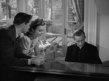Movie still from “Going My Way” (1944), directed by Leo McCarey – A man sitting in front of a piano with two women and a man standing next to him; Medium shot, High angle