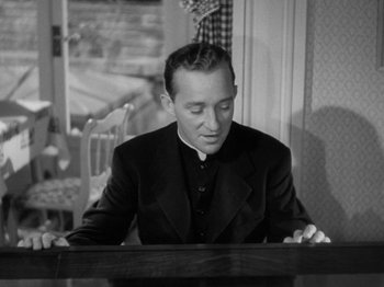 Movie still from “Going My Way” (1944), directed by Leo McCarey – A man sitting at a table in front of a window; Medium shot, High angle