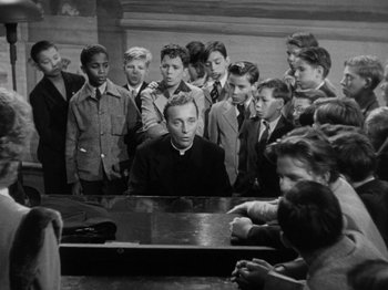 Movie still from “Going My Way” (1944), directed by Leo McCarey – A group of young men standing around an older man; Medium shot, High angle