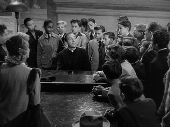 Movie still from “Going My Way” (1944), directed by Leo McCarey – A group of young men and women gathered around a table; Medium shot, High angle