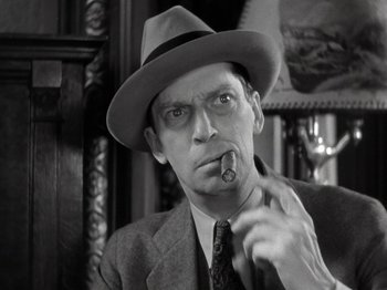 Movie still from “Gold Diggers of 1933” (1933), directed by Mervyn LeRoy – A man in a suit and hat smoking a cigar; Close Up shot, Low angle