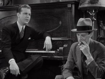 Movie still from “Gold Diggers of 1933” (1933), directed by Mervyn LeRoy – A man sitting next to another man in front of a piano; Medium shot, Low angle