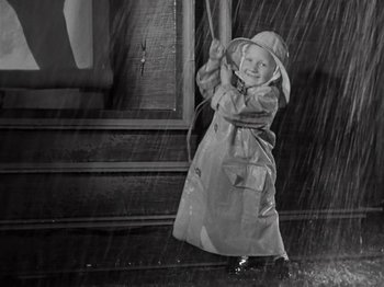 Movie still from “Gold Diggers of 1933” (1933), directed by Mervyn LeRoy – A young child in a raincoat holding onto a swing; Medium shot, High angle