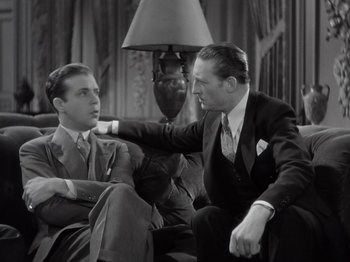 Movie still from “Gold Diggers of 1933” (1933), directed by Mervyn LeRoy – Two men in suits sitting on a couch talking to each other; Medium shot, Low angle
