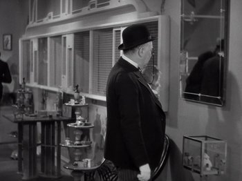 Movie still from “Gold Diggers of 1933” (1933), directed by Mervyn LeRoy – An older man wearing a hat and holding a cigarette; Medium shot, Over the shoulder angle