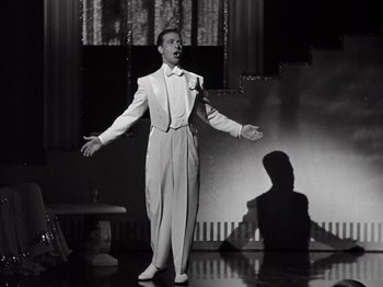 Movie still from “Gold Diggers of 1933” (1933), directed by Mervyn LeRoy – A man wearing a white suit and a bow tie; Medium shot, Low angle