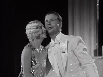 Movie still from “Gold Diggers of 1933” (1933), directed by Mervyn LeRoy – A man and a woman kissing in front of a curtain; Close Up shot, Low angle