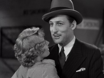 Movie still from “Gold Diggers of 1933” (1933), directed by Mervyn LeRoy – A man and a woman are standing next to each other; Close Up shot, Low angle