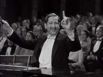 Movie still from “Gold Diggers of 1933” (1933), directed by Mervyn LeRoy – A black and white photo of a man in a tuxedo; Medium shot, Low angle