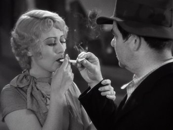 Movie still from “Gold Diggers of 1933” (1933), directed by Mervyn LeRoy – A man and a woman are smoking a cigarette together; Medium shot, Low angle