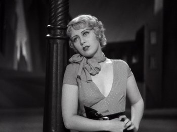 Movie still from “Gold Diggers of 1933” (1933), directed by Mervyn LeRoy – A black and white photo of a woman leaning on a pole; Medium shot, Low angle